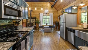 A modern kitchen with a large stove, refrigerator, and wooden ceiling.