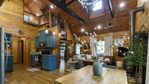 A spacious log cabin interior with a kitchen, dining area, and living room.