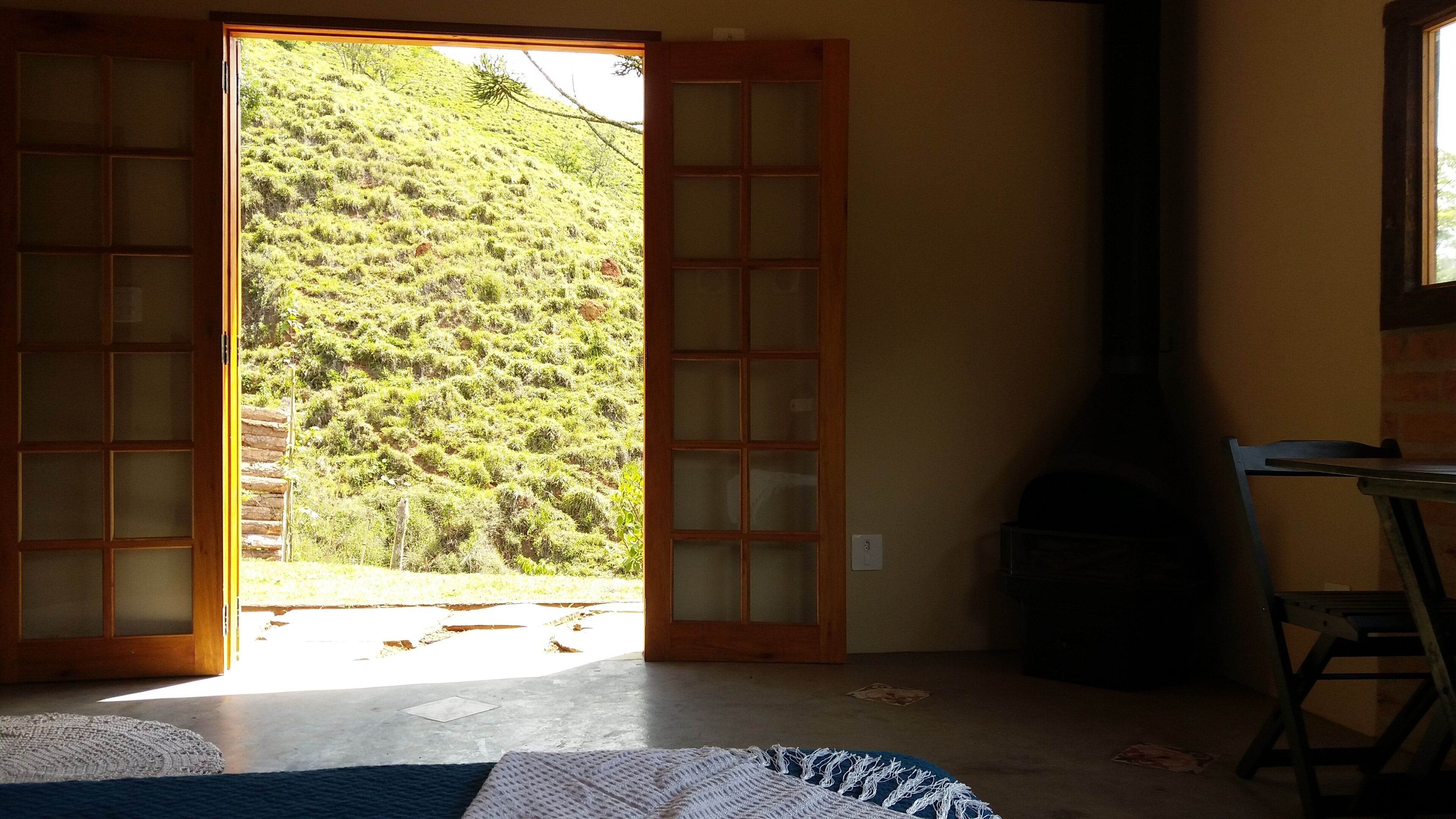A room with a large sliding glass door leading to a hillside view, a fireplace, and a small table.
