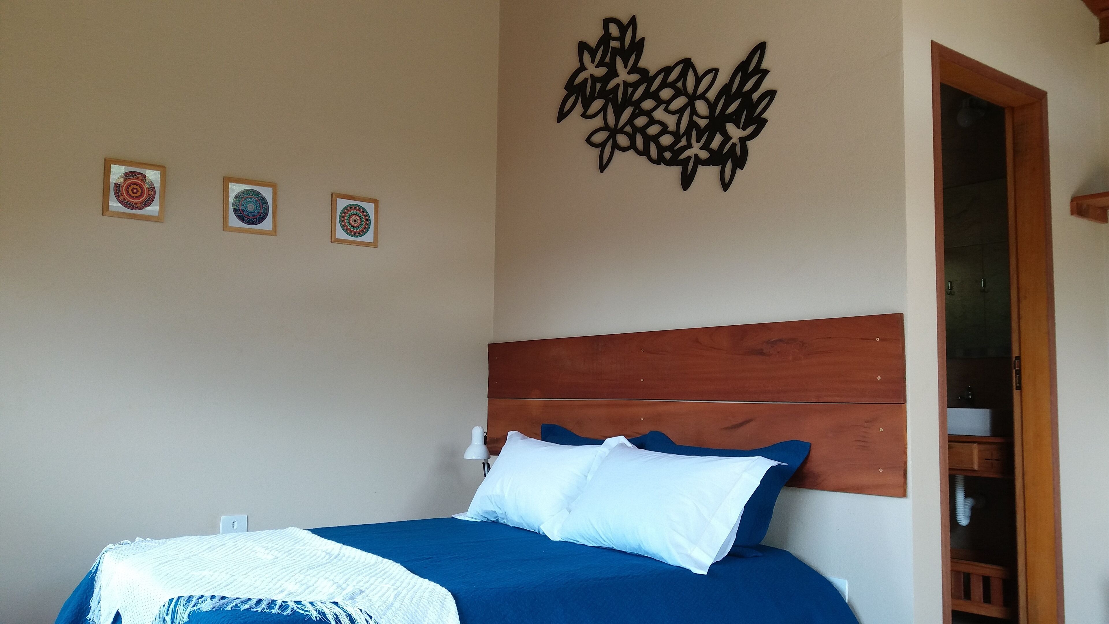 A bedroom with a wooden headboard, a bed with blue bedding, and three framed wall art pieces.