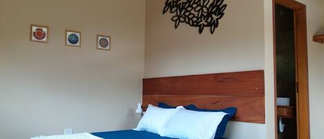 A bedroom with a wooden headboard, a bed with blue bedding, and three framed wall art pieces.