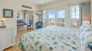 Una camera da letto con un letto grande, una televisione e vista sulla spiaggia.