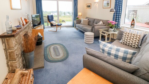 A cozy living room with a sofa, a chair, a small table, and a fireplace. - Hefo'r Grug (Pwllheli)