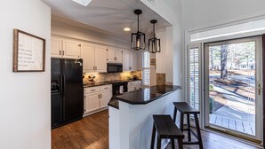 Una cocina moderna con armarios blancos, un refrigerador negro y una isla grande con taburetes de bar.