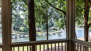 Vista desde una ventana sobre un lago con barcos, árboles y una zona verde.