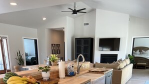 A modern kitchen with a wooden countertop, dark cabinetry, and a built-in dishwasher. - Lux Vineyard Escapes-Ultimate Modern Farm House (Temecula)