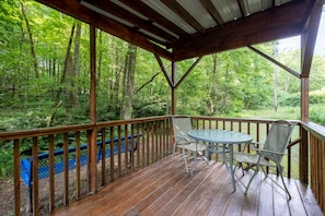 Enjoy a serene forest view from this elevated deck with a table and chairs.
