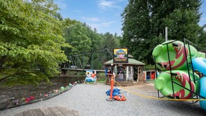 Une zone riveraine avec un quai en bois, un panneau indiquant une activité de « tubing » et des toboggans gonflables.