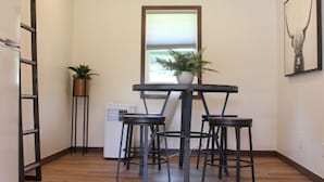 Une cuisine de taille réduite comprenant une table et des chaises, une plante en pot et un réfrigérateur.