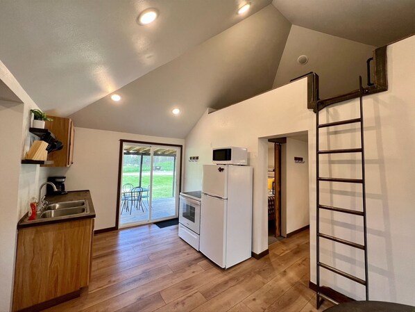 Una cocina compacta con refrigerador, microondas y lavamanos.