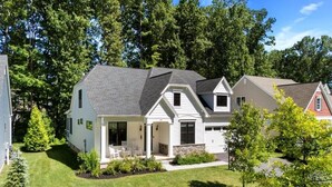 Une maison à deux étages avec un porche à l’avant, un garage et une pelouse bien entretenue.