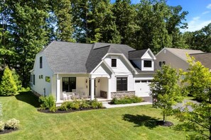 A two-story house with a covered porch, a stone foundation, and a well-maintained lawn.