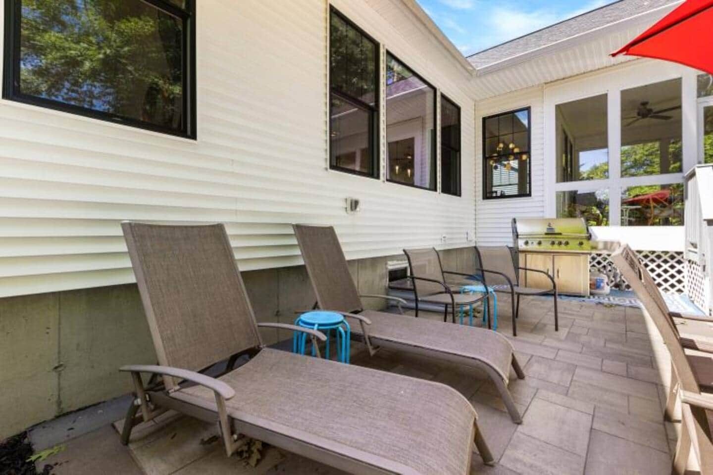 Un patio con mobiliario exterior, una parrilla y un espacio cubierto.