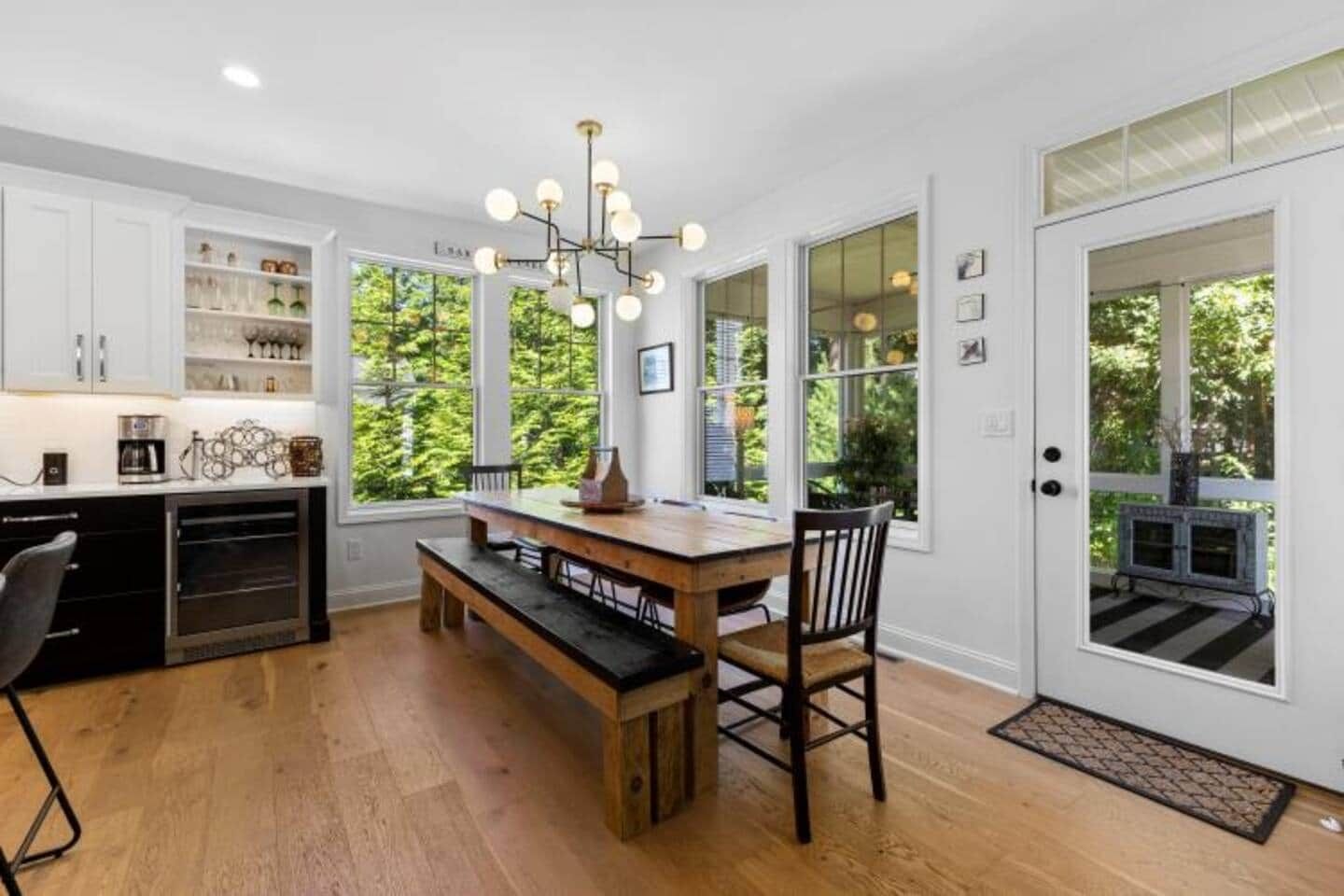 A kitchen with a wooden table, bench, and chairs, a built-in oven, and a chandelier.