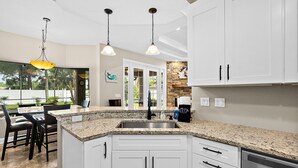 A kitchen with white cabinets, granite countertops, and stainless steel appliances.