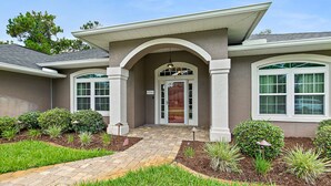 A residential house with a front entrance, a covered porch, and a landscaped garden with a pathway leading to the door.