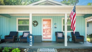 A house with a porch, two wicker chairs, a small table, and an American flag. - Beach Please: Modern Coastal Bungalow Near Waterway and Marshwalk (Oak Island)