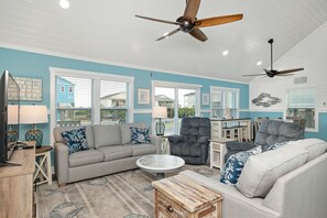 Relax in this inviting living room with a large sofa, round coffee table, and mounted TV.