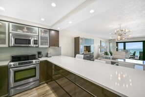 Una cocina moderna con electrodomésticos de acero inoxidable, una isla grande y vista al océano.