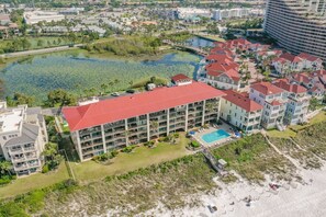 A hotel with a red roof, a swimming pool, and a beach area. - Huntington By The Sea 206. Gulf Front, Community Pool, Free Beach Service. (Miramar Beach)