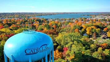 A water tower with 'City of Cadillac, Michigan' text, surrounded by autumn foliage and a lake view.