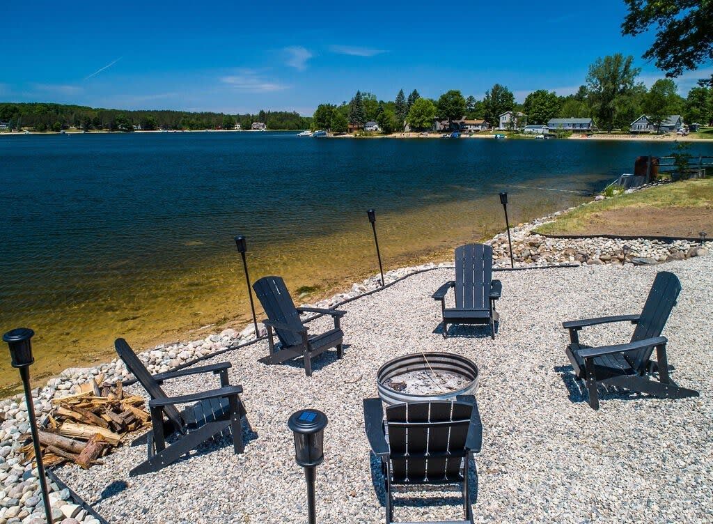 A lakeside seating area with Adirondack chairs and a fire pit.