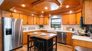 Une cuisine moderne avec des meubles en bois, des appareils électroménagers en acier inoxydable et un îlot central doté de tabourets.