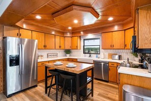A modern kitchen with wooden cabinets, stainless steel appliances, and a central island with stools.