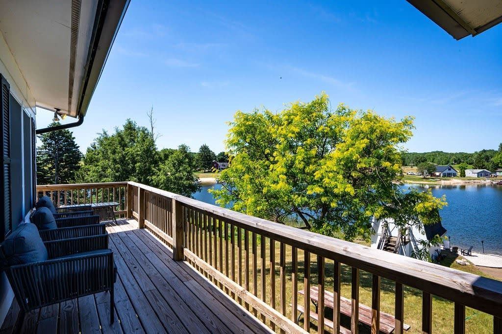 Una terraza de madera con mobiliario exterior y vista a un lago.