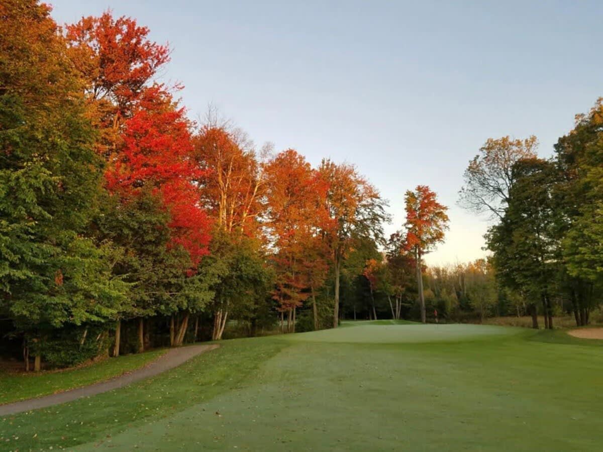 Un parcours de golf avec un tracé bien défini, entouré d’arbres aux feuilles d’automne.