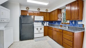 A kitchen with wooden cabinets, a stainless steel refrigerator, a white stove, and a blue-tiled backsplash. - Private A-Frame w/Kayaks on Canal newly renovated (Granbury)