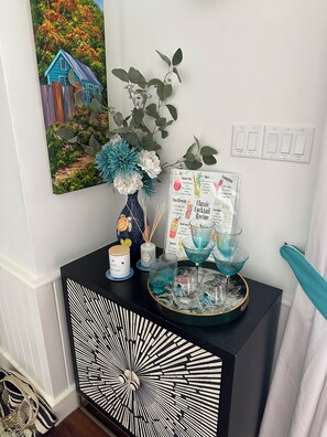 A black and white patterned cabinet with a decorative vase, a menu, and blue glassware on top. - Pool fronted Luxury re furbished Villa with Fairmont beach club access card. (Porters)