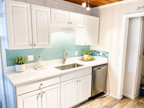 A kitchen with white cabinets, a stainless steel sink, and a dishwasher.