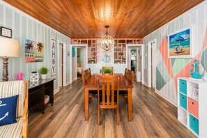 A dining area with a wooden table and chairs, a chandelier, and nautical-themed decor.