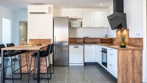 A modern kitchen with a wooden countertop, a built-in microwave, a stainless steel refrigerator, and a black range hood. - Villa A Cucina (Propriano)