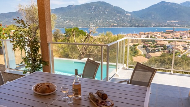 A table with a loaf of bread, a bottle of wine, and a meat platter. - Villa A Cucina (Propriano)