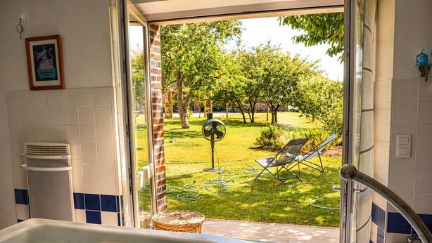 A bathroom with a bathtub, a window, and a view of a garden. - LA MELINOTHE (Paisy-Cosdon)