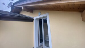 Ein Gebäudeeck mit einem Fenster, einer Satellitenschüssel und einem kleinen, runden Gegenstand an der Wand.