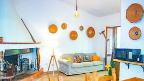 Un salon chaleureux avec une cheminée, un canapé et un coin repas.