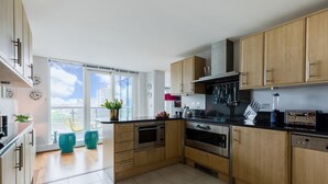 A modern kitchen with wooden cabinets, stainless steel appliances, and a large window offering a city view. - HUGE THAMES VIEW LUXXE NOMAD DESIGN HOME (London)