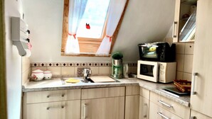 Une cuisine compacte dotée d’une fenêtre, d’un four à micro-ondes, d’une bouilloire et d’un évier.