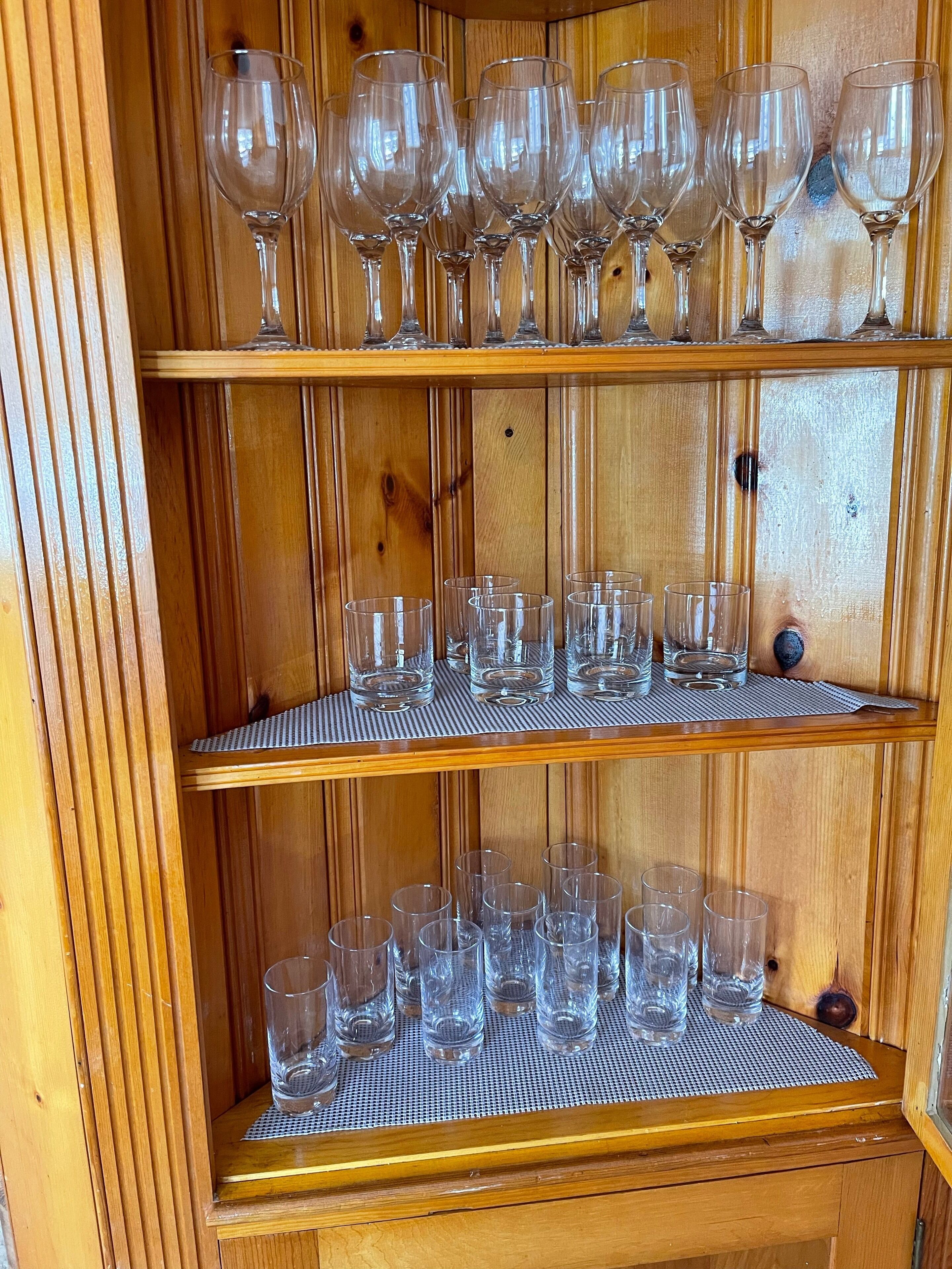 A wooden wine rack with multiple shelves holding various types of wine glasses and tumblers.