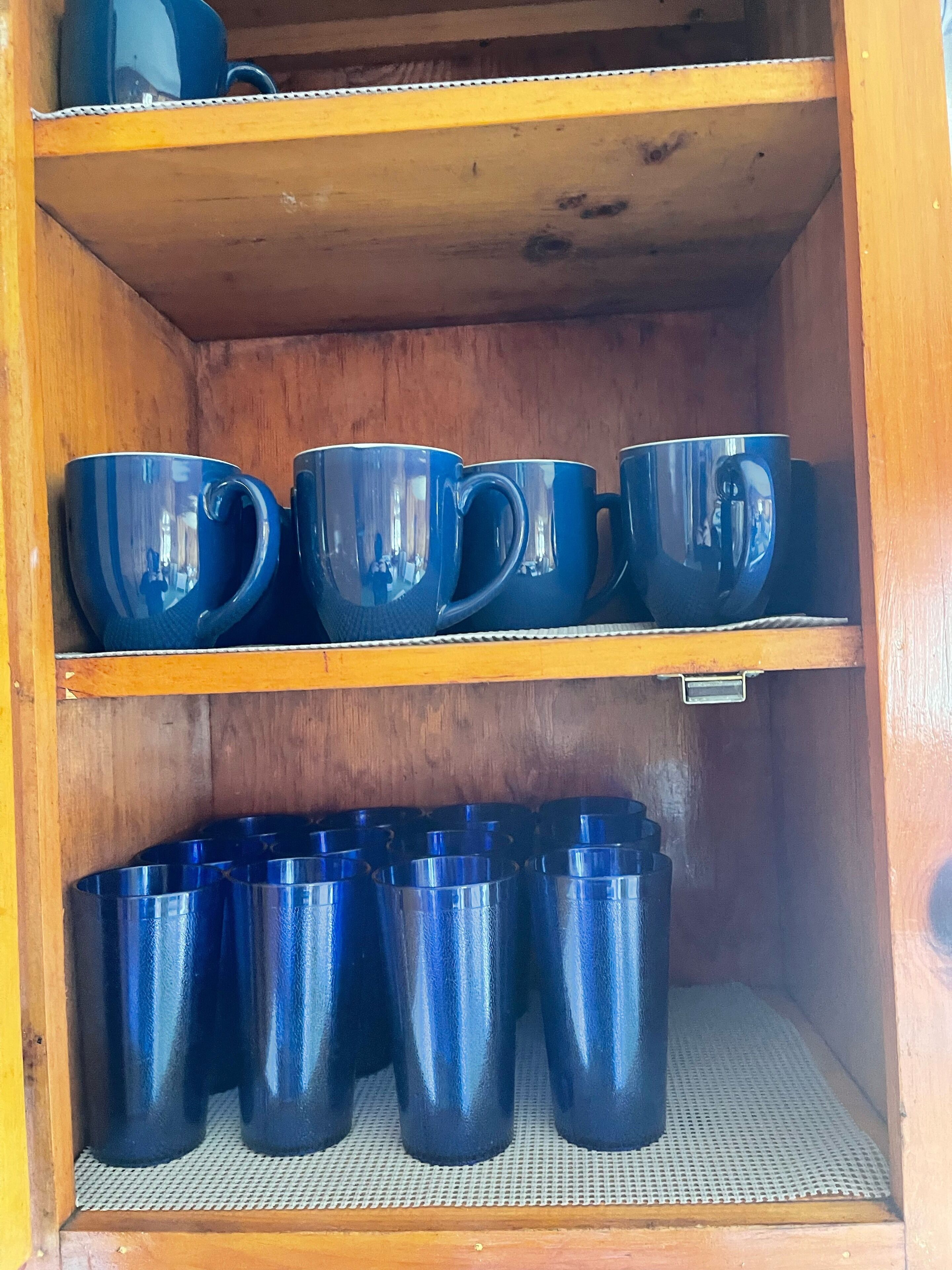 Ein Holzregal mit blauen Tassen und Thermoskannen.