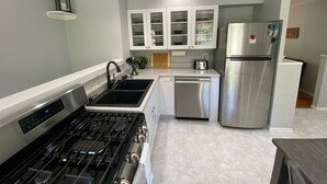 A modern kitchen with a stainless steel gas stove, a sink, a dishwasher, and a refrigerator. - Remodeled Home - Near Faurot Field! (Columbia)