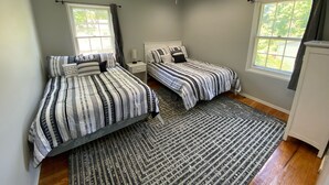 A bedroom with two beds, a ceiling fan, and large windows. - Remodeled Home - Near Faurot Field! (Columbia)