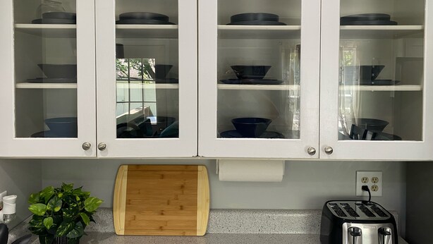 A kitchen with white cabinets, a wooden cutting board, a toaster, and a potted plant. - Remodeled Home - Near Faurot Field! (Columbia)