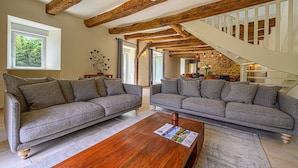 A modern living room with two grey sofas, a wooden coffee table, and exposed wooden beams. - Ker Case A Nou - Longère à la campagne (Monterblanc)