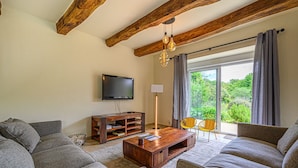 A living room with a flat-screen TV, wooden coffee table, grey sofas, and a large window with curtains. - Ker Case A Nou - Longère à la campagne (Monterblanc)