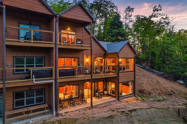 A multi-story wooden cabin with balconies, large windows, and outdoor seating areas.