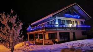 A snow-covered landscape with a house illuminated by blue lights. - Le Château D'Ancelle (Ancelle)